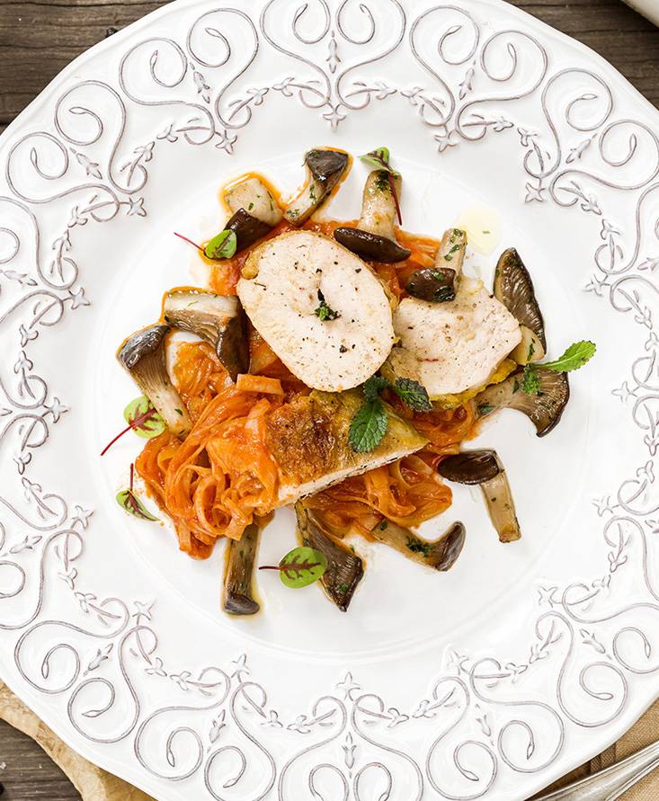 Suprême vom perlhuhn mit in tomaten geschmortem lauch und gedünsteten kräuterseitlingen